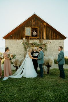 the bride and groom are getting married in front of their rustic wedding venue with sheep