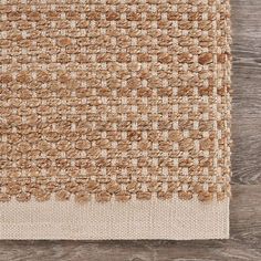 an area rug with brown and white squares on the floor next to a wooden wall