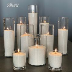 a group of candles sitting on top of a table next to each other in glass vases