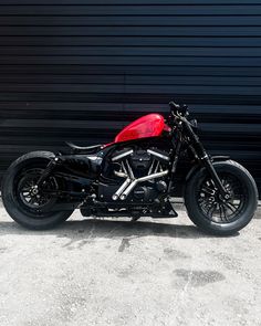 a red and black motorcycle parked in front of a garage door