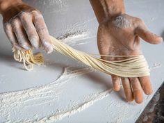 a person is pulling pasta out of the wall with their hands and holding it in front of them