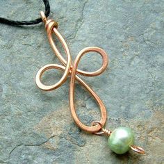 a copper pendant with a green pearl hanging from it's end on a black cord