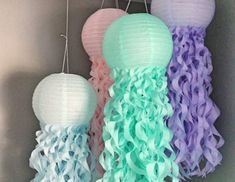 two pictures of different colored paper lanterns hanging from hooks on the wall, one with green and purple ruffles