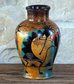 a colorful vase sitting on top of a wooden table