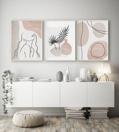 three abstract paintings hang on the wall above a white cabinet in a modern living room