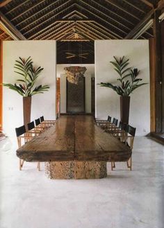 an image of a dining room table in the middle of a room with potted plants