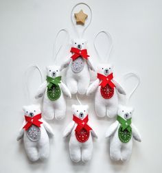 six white teddy bears with red and green bows on their ears are hanging from a star ornament