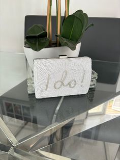 a white purse sitting on top of a glass table next to a potted plant