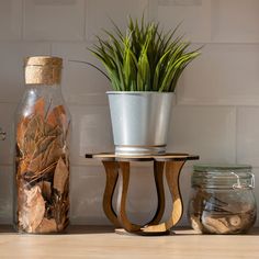 a potted plant sitting on top of a wooden stand next to a glass jar