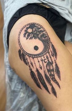 a woman's thigh with a black and white dream catcher tattoo on her leg