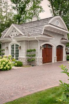 a small house with two garages on the front and one in the back, surrounded by greenery