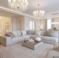 a living room filled with furniture and a chandelier hanging above the couches