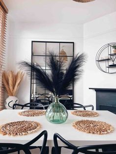 a dining room table with black chairs and a vase filled with feathers