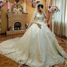 a woman in a white wedding dress standing next to a fireplace with flowers on it