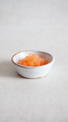 a small white bowl filled with food on top of a table next to an orange slice