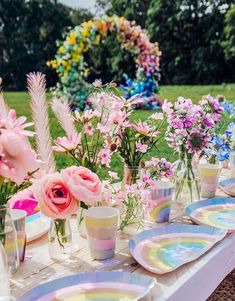 a table set up with flowers and plates for an outdoor dinner party in the garden