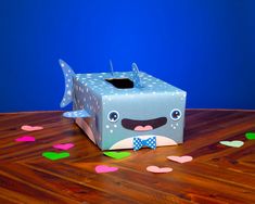 a blue box with a face and bow tie sitting on top of a wooden table