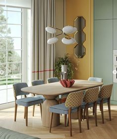 a dining room table surrounded by blue and yellow chairs with an oval mirror on the wall