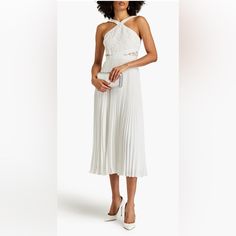 a woman is wearing a white dress with pleated skirt and high heeled shoes