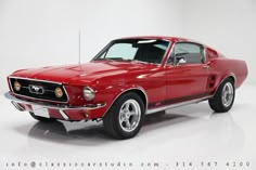 a red mustang muscle car parked in a white room