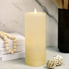 a white candle sitting on top of a table next to a book and bead necklace