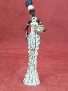 an african woman figurine holding a potted plant on a red tablecloth