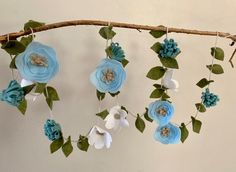 blue and white flowers are hanging from a branch