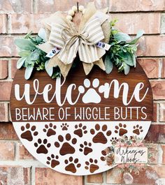 a welcome sign on the side of a brick wall with dog paw prints and greenery