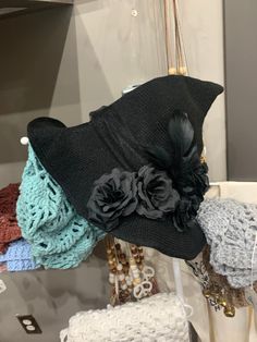 several hats are hanging on a rack in a store display case, some with black and gray flowers