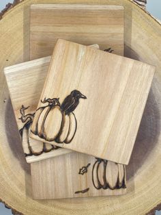 three wooden coasters sitting on top of a wood plate with black birds and pumpkins