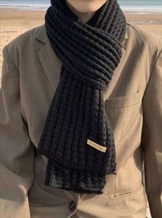 a man wearing a hat and scarf on the beach