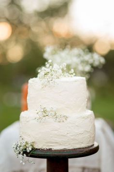 a white wedding cake sitting on top of a wooden table