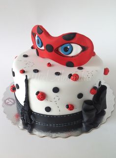 a decorated cake with red and black decorations on it's face, sitting on top of a doily