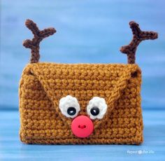 a crocheted purse with a red nose and antlers on the front, sitting on a blue surface