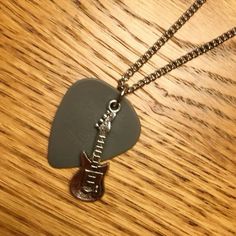 a guitar pick with a metal chain attached to it on top of a wooden table