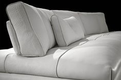 a white couch with pillows on it in front of a black background and flooring