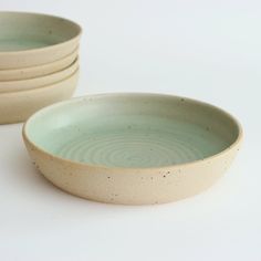 four white and green bowls sitting on top of each other next to eachother