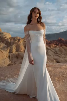 a woman in a wedding dress standing on top of a mountain