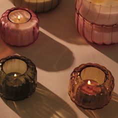 three candles sitting next to each other on top of a white table covered in glass