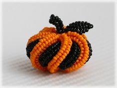 an orange and black beaded brooch sitting on top of a white surface