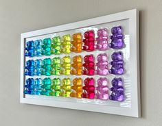 there is a rainbow teddy bear wall hanging on the wall in front of a white frame