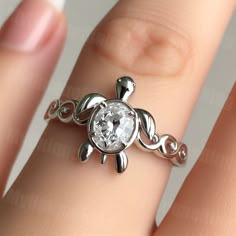 a close up of a person's hand holding a ring with a turtle on it