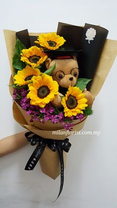 a bouquet of sunflowers with a teddy bear wearing a hat and glasses on it