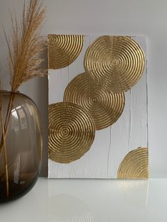 a white and gold art piece sitting on top of a table next to a vase