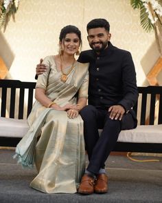 a man and woman are sitting on a bench smiling at the camera while posing for a photo