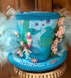 This is a great hat for a tea party or beach theme get together .  This Tea Party Hat is a medium  size.  Measures approx. 6"  and 4.5" tall plus decorations  Has blue & turquoise feathers. It has 2 hat pins. Mermaid tail pick and mermaid  pick on hat.  Hat has white elastic to hold on your head. Elastic goes over your head behind ears &  under your hair. Also included is 2 clips to help stay on if needed. Carnival Mini Hat With Curved Brim, Whimsical High Crown Hat For Themed Events, Fun Mini Hats For Carnival Themed Events, Whimsical Costume Hats With Curved Brim For Party, Whimsical Costume Hat With Curved Brim For Party, Whimsical High Crown Hat For Party, Whimsical High Crown Party Hat, Handmade Themed Costume Hats And Headpieces For Themed Events, Handmade Costume Hats And Headpieces For Themed Events