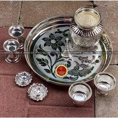 an assortment of silver dishes and cups on a tray with the lid down, next to each other