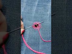 someone is stitching something on the side of a blue piece of cloth with pink thread