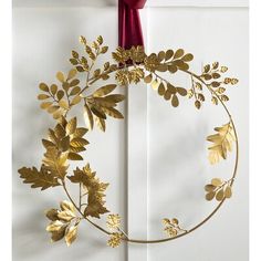 a gold wreath hanging on the side of a door with a red ribbon around it