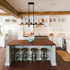 a kitchen island with four stools in front of it